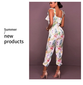 Detailed close-up of white summer jumpsuit with tropical pineapple and floral print patterns