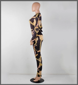 Detail of slim fit long sleeve jumpsuit with gold chain and baroque print on black fabric