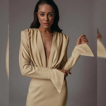Detail view of khaki V-neck dress featuring structured shoulder pads and wide flared cuffs