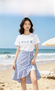 Gros plan sur t-shirt blanc avec texte Nice et jupe à rayures bleues à la plage