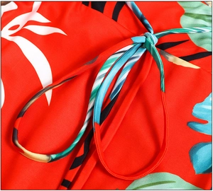 Detailed close-up of tropical leaf floral print on red dress featuring tie-up waist knot