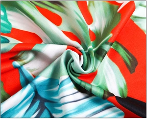 Detail of red tropical floral fabric showing leaf prints and soft textile texture