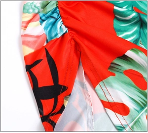 Detailed view of red tropical leaf print dress with side ruching and neat stitching