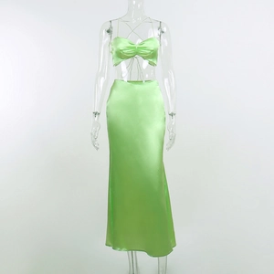 Detail view of bright green satin two-piece set featuring cross strap halter top and skirt