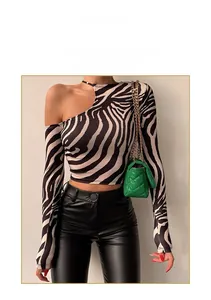 Detail van zebraprint top met lange mouwen en een groene schoudertas met ketting