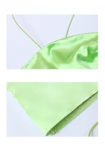 Detail of light green satin dress showing thin strap and smooth hemline stitching