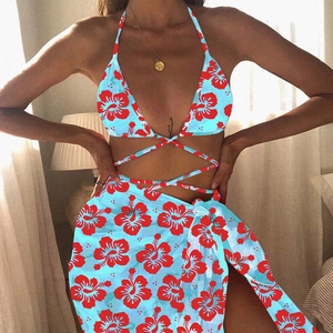 Three-piece light blue bikini set with red hibiscus print and matching sarong skirt