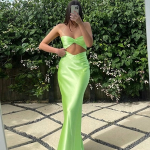 Lime green satin maxi dress with waist cut-outs and spaghetti straps in garden setting