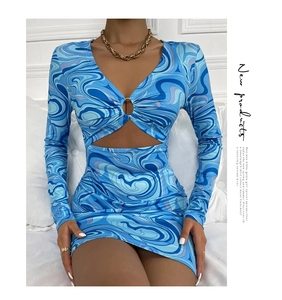 Détail du décolleté en V avec anneau métallique sur une robe bleue à imprimé marbré
