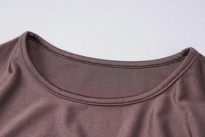 Detail view of a round neck on a brown long sleeve dress with fine stitching and silk gloss