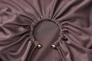 Detailed view of cutout design with metal ball accents and pleated fabric on brown dress