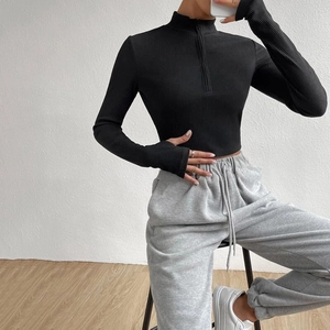 Slim fit black ribbed knit top featuring a high neck half-zipper and thumbhole sleeves