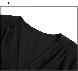 Gros plan du col en V avec coutures fines et détails plissés sur une robe noire élégante