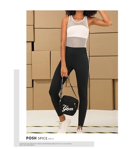 Detail of high-waisted black yoga pants and mesh tank top on model in industrial setting