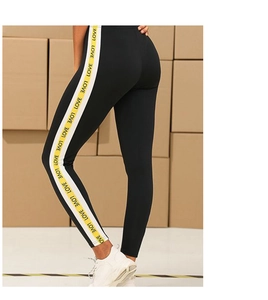Detail of yellow and white striped side tape with LOVE letter print on black yoga leggings