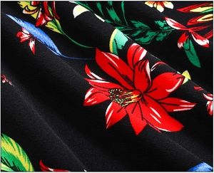 Vue macro montrant les détails de l'imprimé floral tropical rouge sur tissu noir