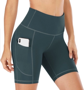 Detail of high-waist yoga shorts with side pocket holding a smartphone in dark green