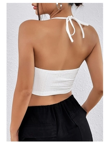 Dettaglio del crop top bianco con scollo all'americana, schiena scoperta e trama jacquard