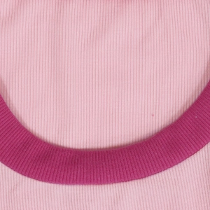 Détail de la maille côtelée rose avec collet cousu de couleur rouge rose vif élégant