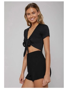 Dettaglio del crop top nero con scollo a V e fiocco e pantaloncini a vita alta coordinati
