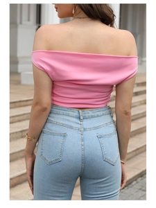 Dettaglio del top rosa a spalle scoperte con pieghe e taglio in vita irregolare alla moda