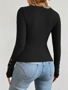 Detail of black rib-knit sweater sleeve featuring decorative gold buttons and texture