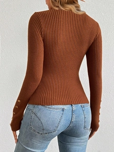 Detail view of ribbed brown knit sweater sleeves featuring elegant gold button accents