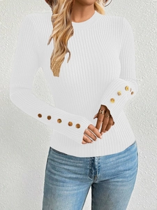 Detail of white ribbed knit sweater featuring elegant gold buttons on the sleeve cuffs
