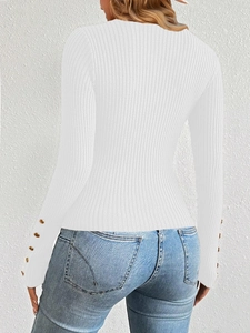 Close-up of white ribbed knit sweater featuring elegant gold button cuffs and slim fit texture