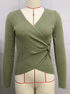 Close-up of sage green ribbed knit top with wrap-around V-neck and tortoiseshell buckle