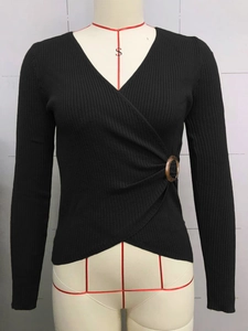 Detail of black ribbed knit sweater with wrap V-neckline and amber buckle closure