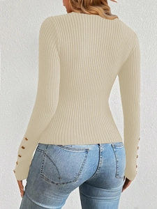 Close-up of beige ribbed knit sweater featuring elegant gold buttons on the sleeves