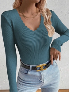 Detail of scalloped V-neckline and ribbed knit texture on a teal long-sleeve sweater