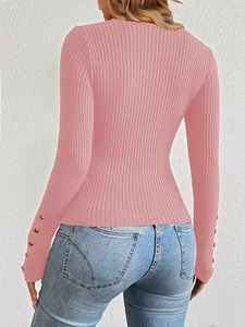 Close-up of pink ribbed knit top featuring elegant golden buttons on the sleeve cuffs