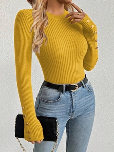 Detail of ginger yellow ribbed knit sweater featuring gold button accents on cuffs