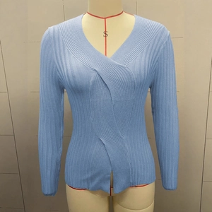 Detailed close-up of light blue V-neck knitted top with vertical ribbed texture and slit hem