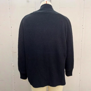 Vista posteriore di un cardigan nero a maglia grossa con polsini a coste e texture