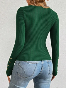 Close-up of ribbed knit green sweater sleeve featuring elegant gold decorative buttons