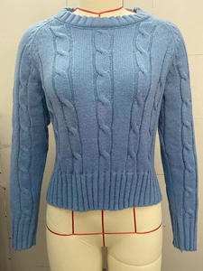 Detail showing the cable knit texture and ribbed neckline of this light blue crew neck sweater