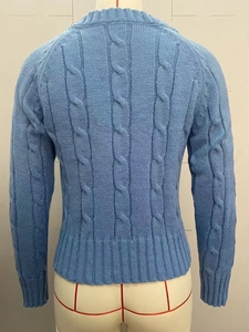 Back view of light blue cable-knit sweater with ribbed cuffs and hem on mannequin