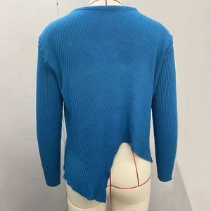 Détail d'un pull en maille côtelée bleue avec ourlet fendu irrégulier asymétrique