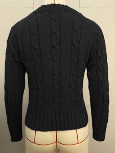 Detailed view of black cable knit sweater back featuring heavy texture and ribbed hemline