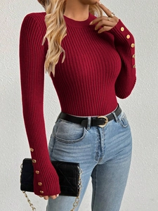 Close-up of red ribbed knit sweater featuring golden decorative buttons on cuffs
