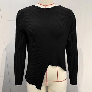 Détail d'un pull en maille côtelée noire avec une coupe d'ourlet asymétrique stylée