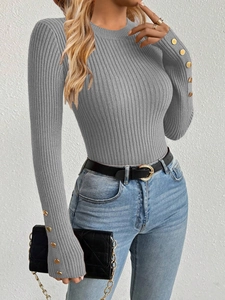 Detailed view of grey ribbed knit sweater sleeve featuring decorative gold buttons