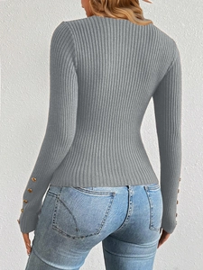 Detail of grey ribbed knit sweater featuring gold button accents on long sleeves