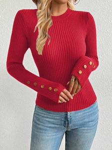 Close-up of red ribbed knit sweater featuring elegant gold buttons on the sleeve cuffs