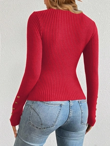 Detail of red ribbed knit sweater featuring gold decorative buttons on the sleeve cuffs