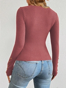 Detail view of pink ribbed knit sweater with gold decorative buttons on the sleeve cuffs