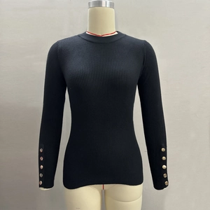 Detail view of ribbed knit texture and golden buttons on sleeves of black sweater